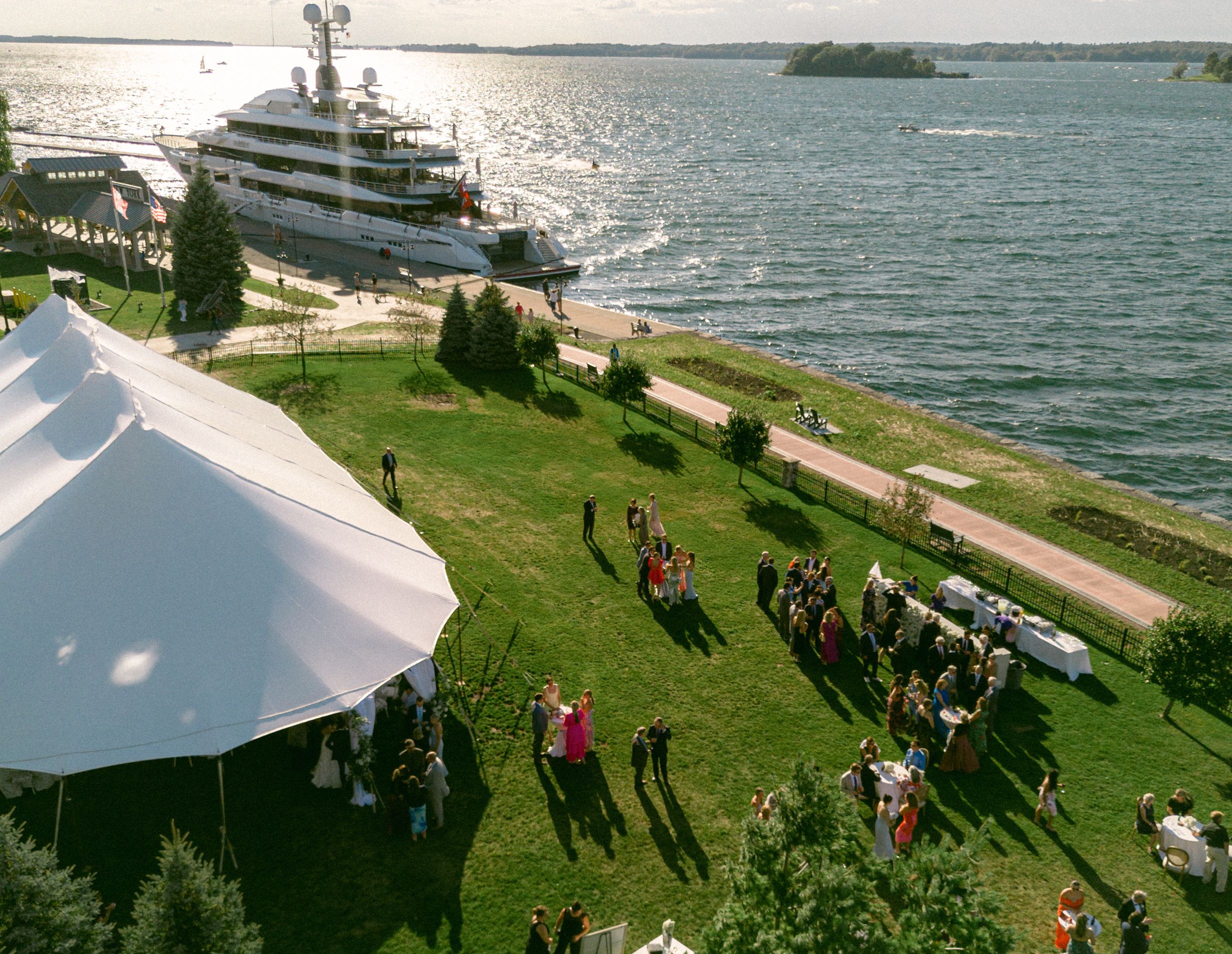 An aerial view of the front lawn of the 1000 Islands Harbor Hotel with a party tent set up and a large boat docked right offshore