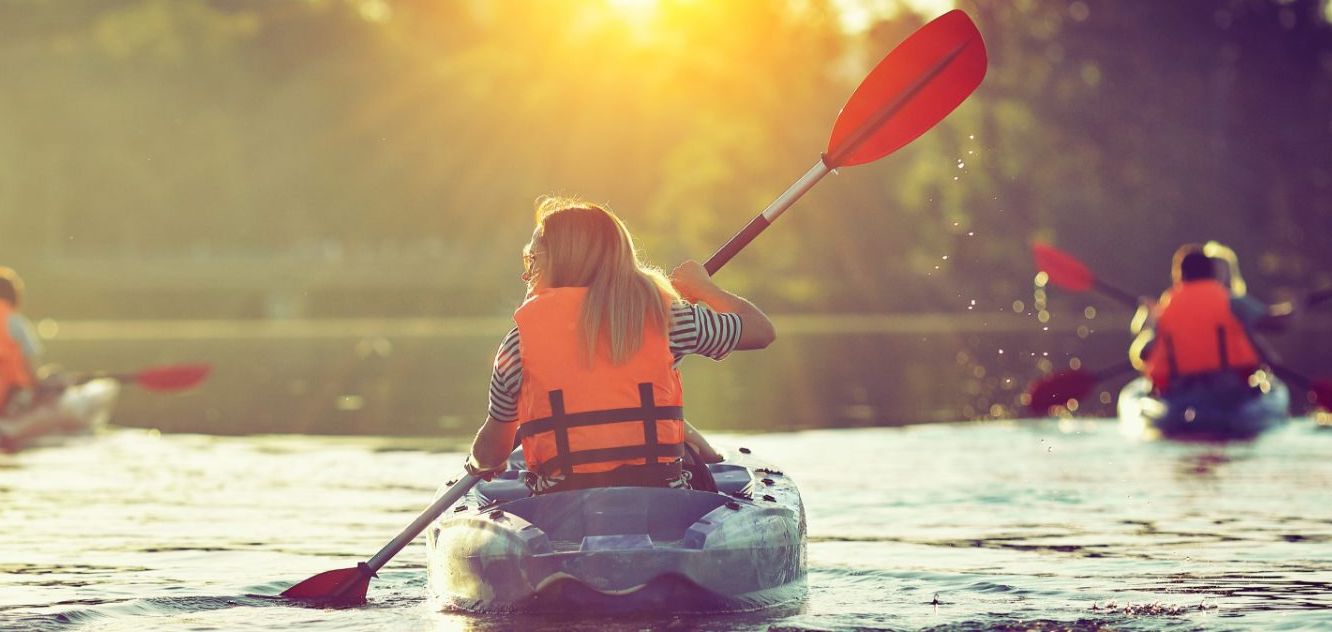 A group of kayakers on the water with bright orange life jackets