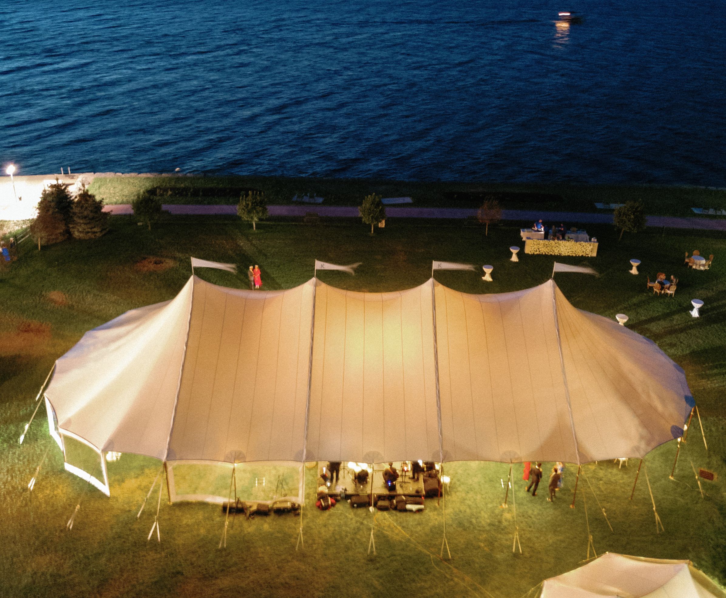 A illuminated tent on the front lawn of the 1000 Islands Harbor Hotel with the St Lawrence River in the background