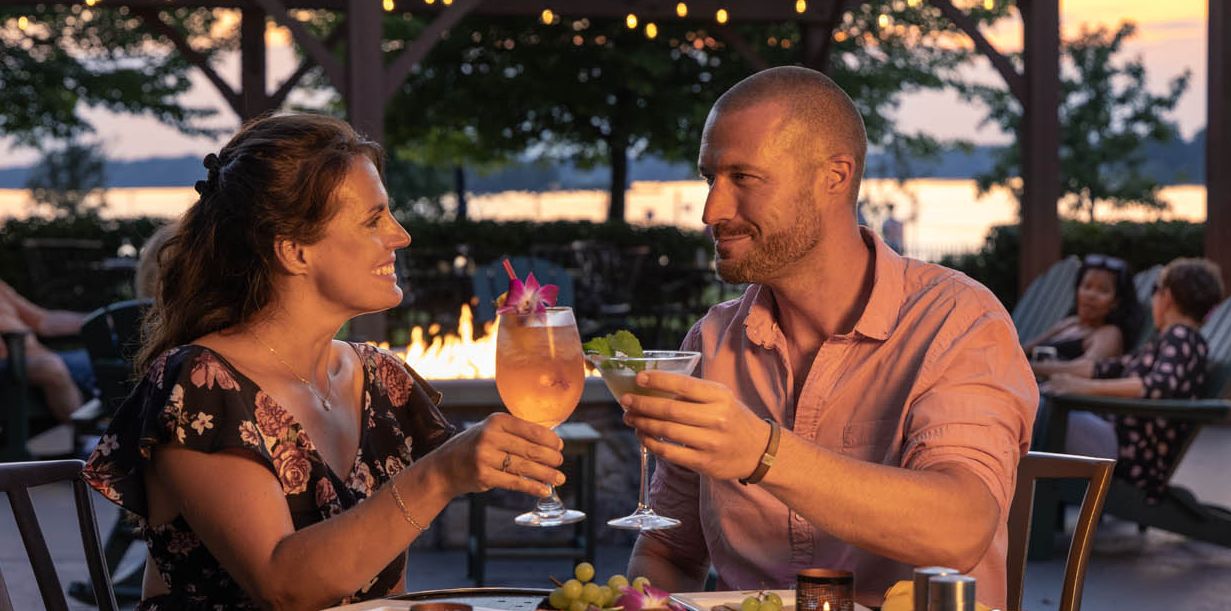 A couple toasts their beverages while dining al fresco at the 1000 Islands Harbor Hotel